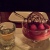 a round dish filled with chocolate and raspberries on a plate next to a shot glass